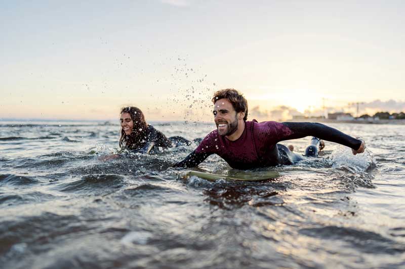 couple in ocean swimming on surf boards